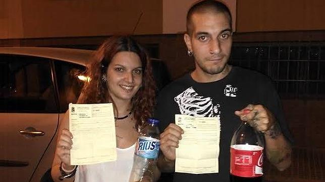 Una de las parejas multadas muestra las denuncias y los refrescos que tomaban en la vía pública