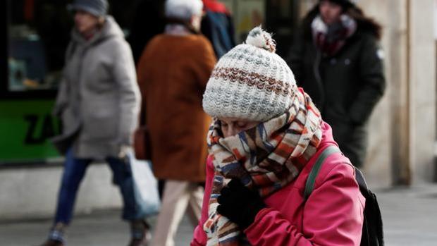 Una mujer se protege del frío con bufanda y gorro