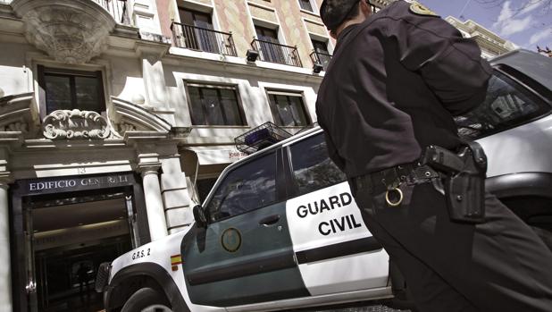 Un agente junto a un furgón de la Guardia Civil durante una redada en Sevilla