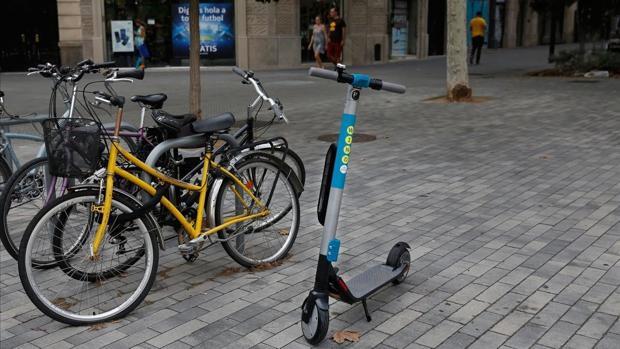Patinete eléctrico, junto a bicicletas en la acera