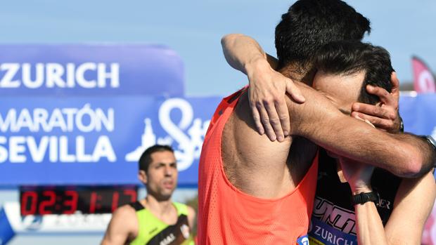 Dos participantes se abrazan tras cruzar la meta del Zurich Maratón Sevilla