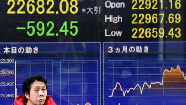 Un peatón pasa delante de una pantalla con los valores de la Bolsa de Tokio, en Japón