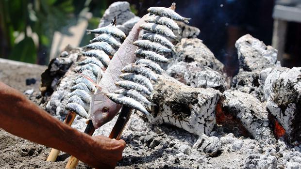 Un espetero preprara unas sardinas en un chiringuito de Málaga