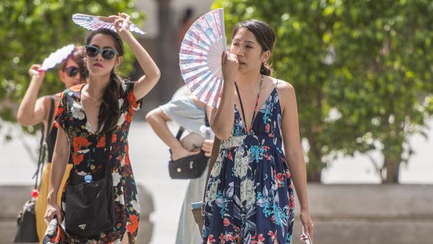 Dos turistas alivian el fuerte calor de Sevilla con unos abanicos