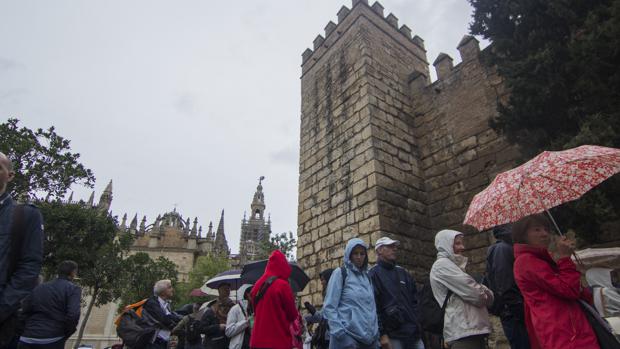 Varios turistas, bajo la lluvia en la cola para visitar el Alcázar de Sevilla