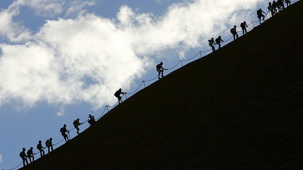 Turistas escalando el monolito de Uluru